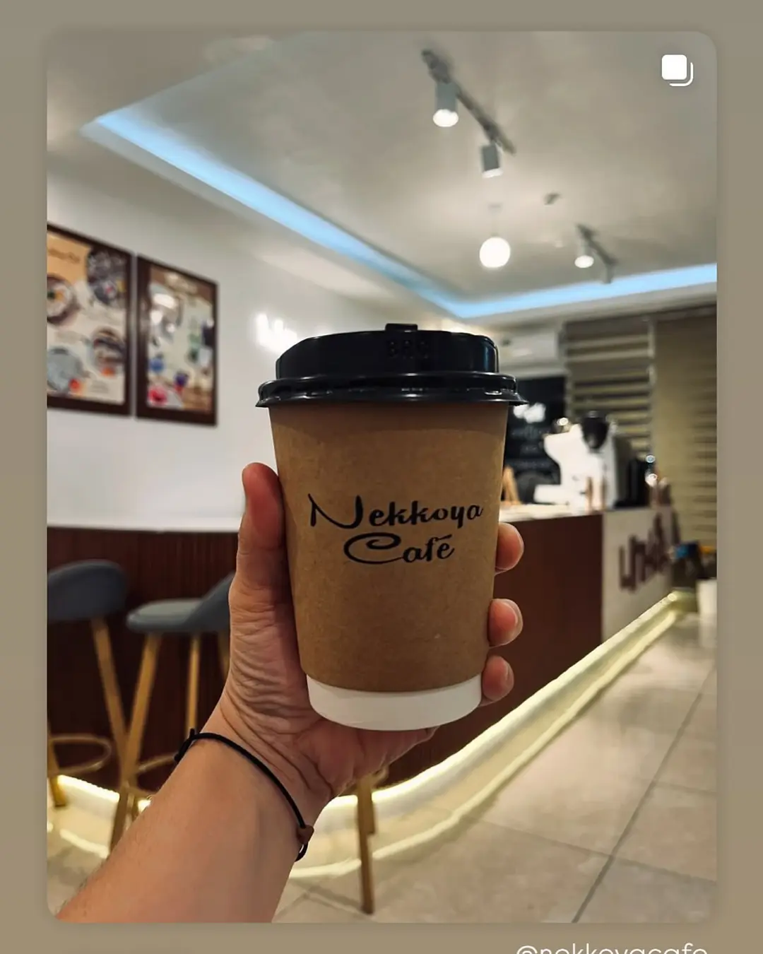 A hand raising a Nekkoya Café cold cup in front of the 내꺼야 counter