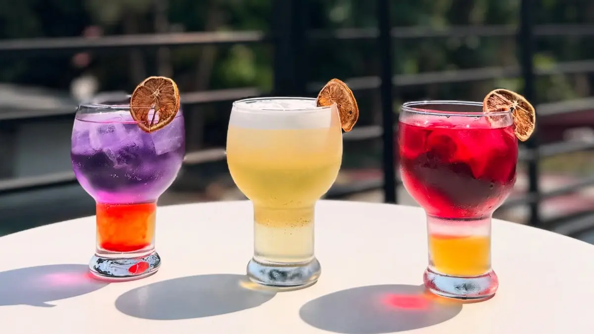 Three colorful Nekkoya drinks catching golden-hour light on the terrace