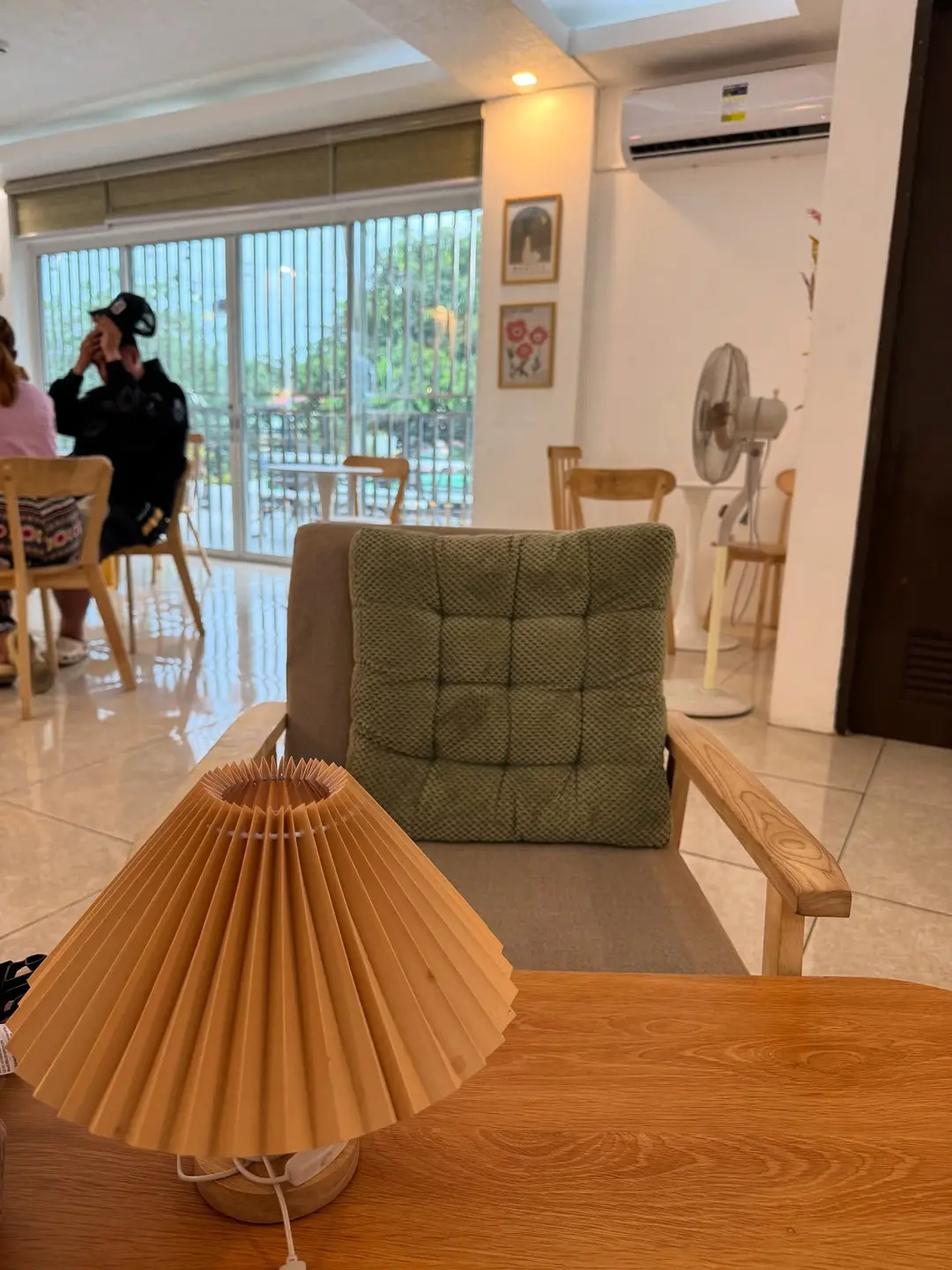 Soft lounge corner of the café with a green armchair and pleated lamp