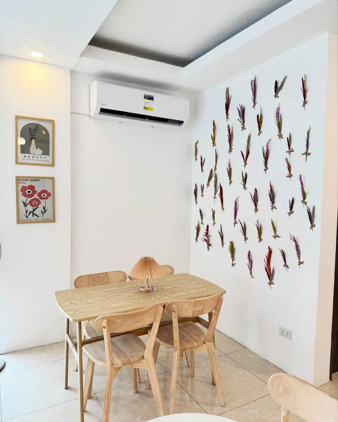 Light-wood café tables beneath a wall of pressed flowers